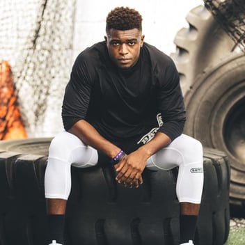 football player sitting on tire wearing compression tights