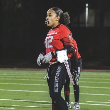 Young woman playing flag football on a field wearing 
