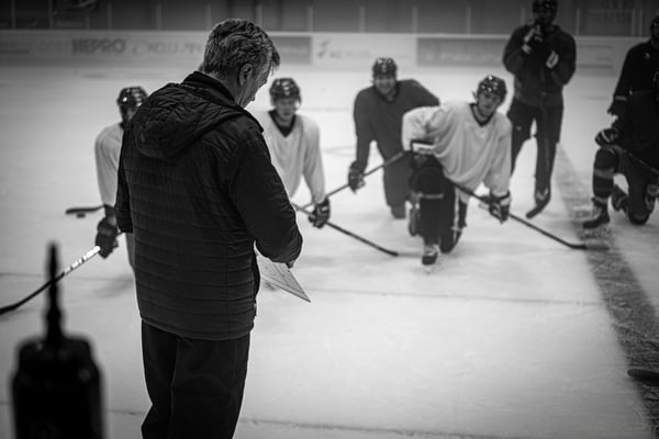 group of hockey players in a huddle with their coach